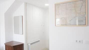 Un baño con un radiador blanco, un armario de madera, un espejo y un mapa enmarcado en la pared.