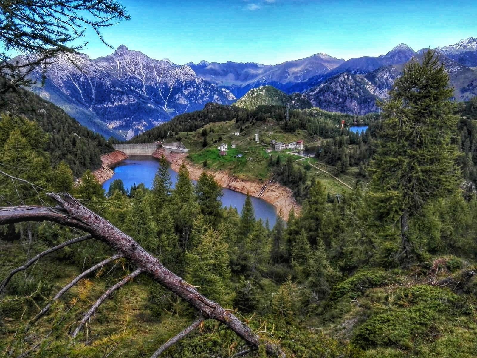 A mountainous landscape with a lake, a bridge, and buildings.