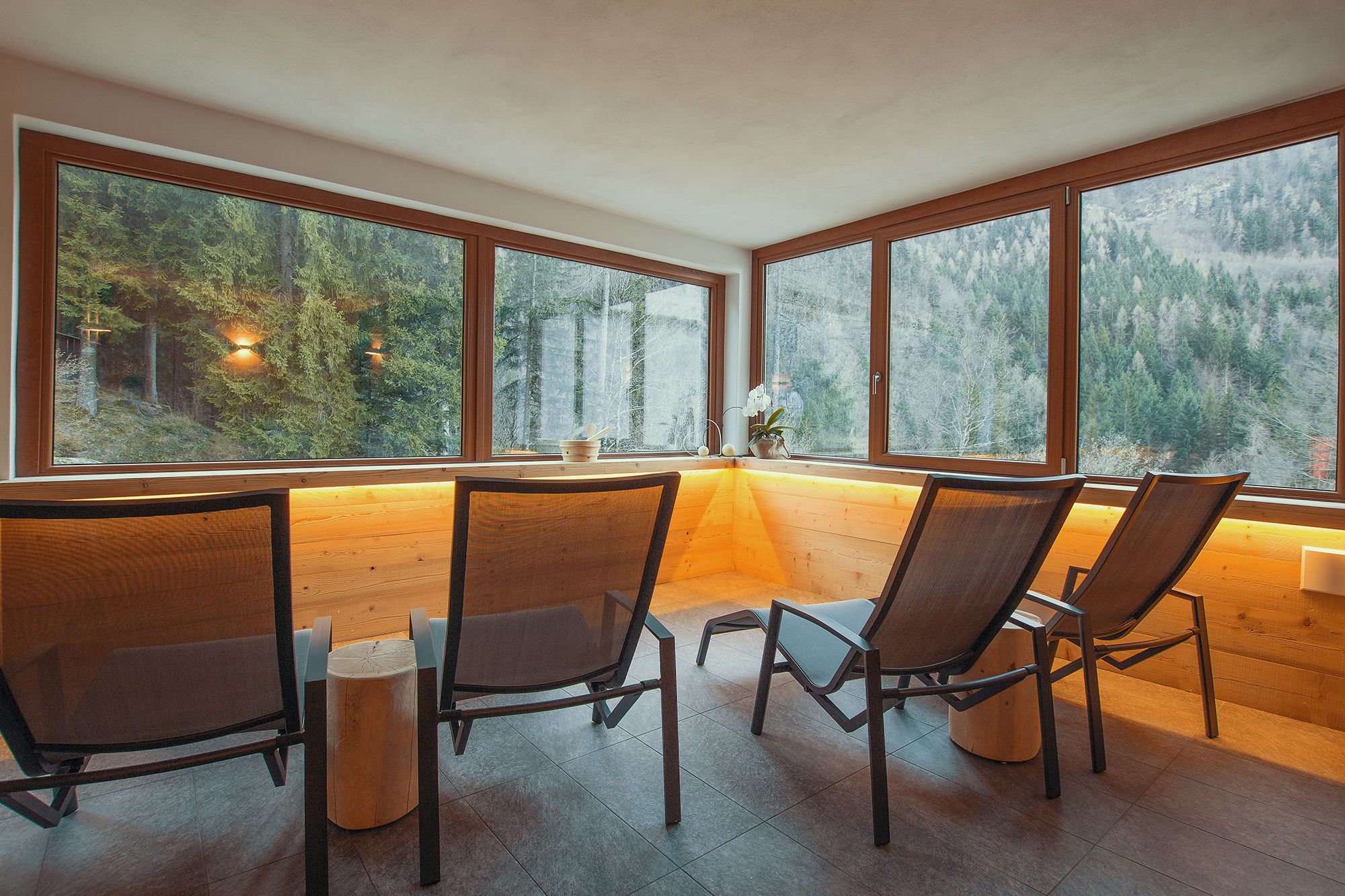 Ein modernes Interieur mit großen Fenstern, Holzmöbeln und Blick auf einen Wald.