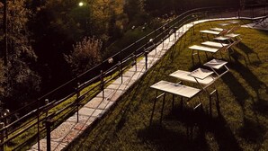 Un parque con un sendero pavimentado, bancos y mesas dispuestas para comer al aire libre.