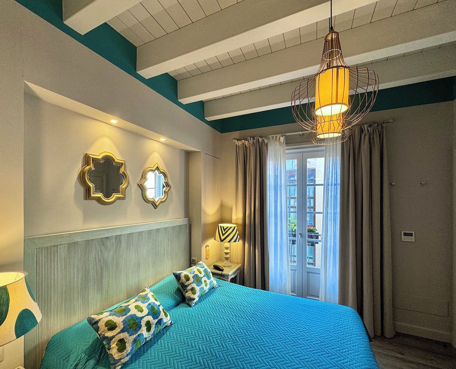 A bedroom with a bed, a nightstand, a lamp, and a window with curtains.
