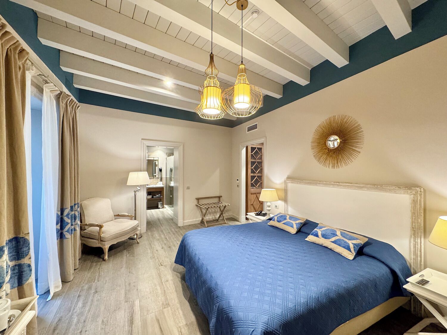 A bedroom with a large bed, two bedside tables, a chair, and a mirror.