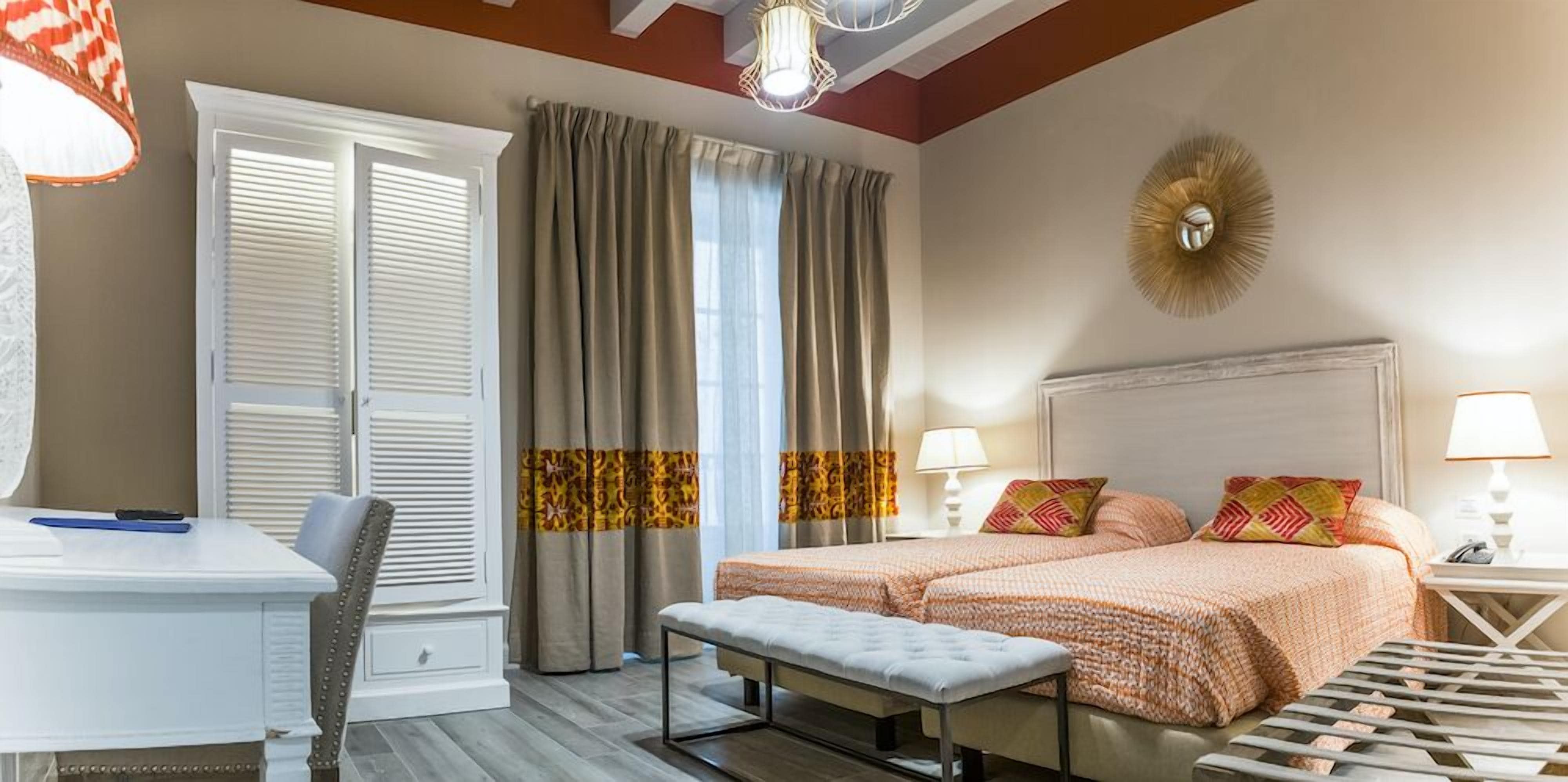 A hotel room with a bed, bedside tables, a desk, and a chair.