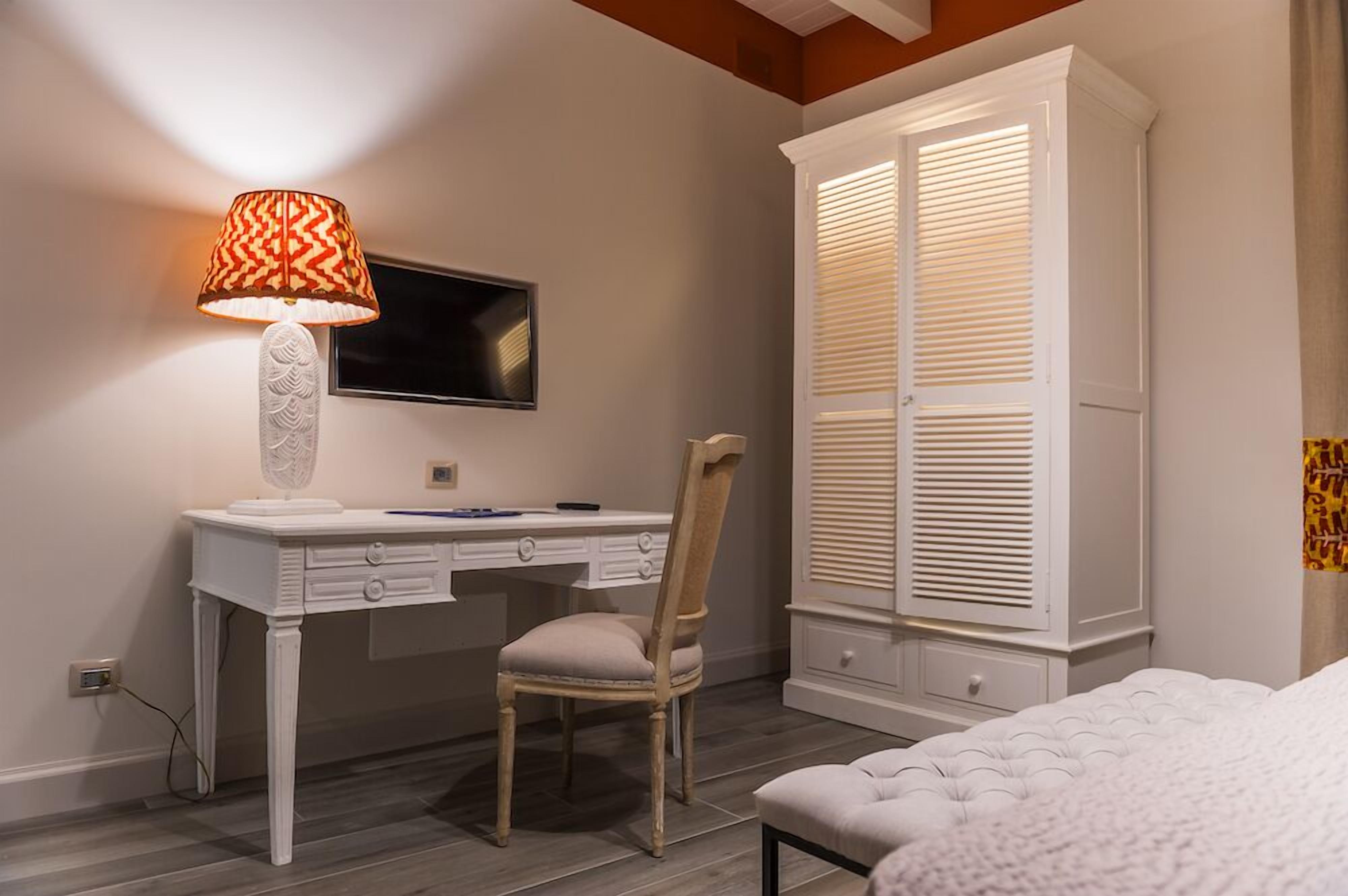 Un dormitorio con una cama, un escritorio con silla, un televisor y un armario.