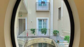Una ventana circular con vista al interior de un edificio, que incluye una escalera, balcones y ventanas.
