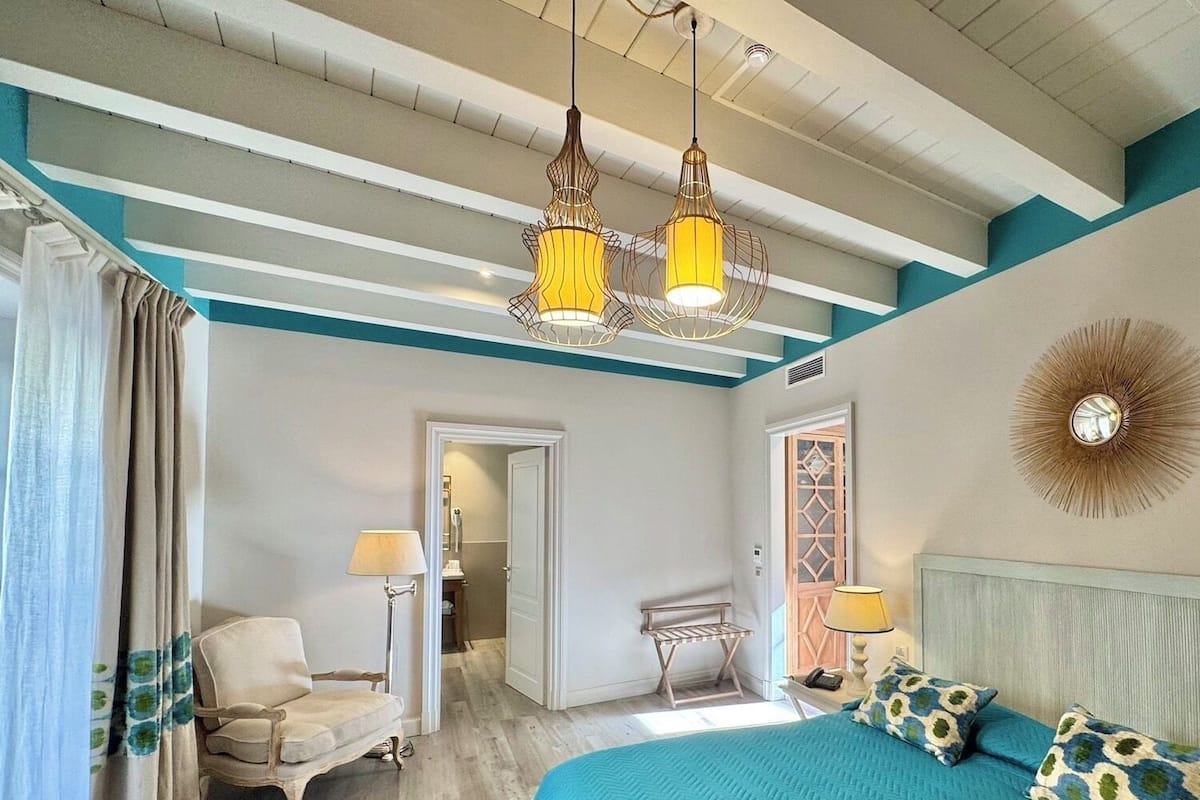 A bedroom with a bed, a chair, a lamp, and a ceiling light fixture.