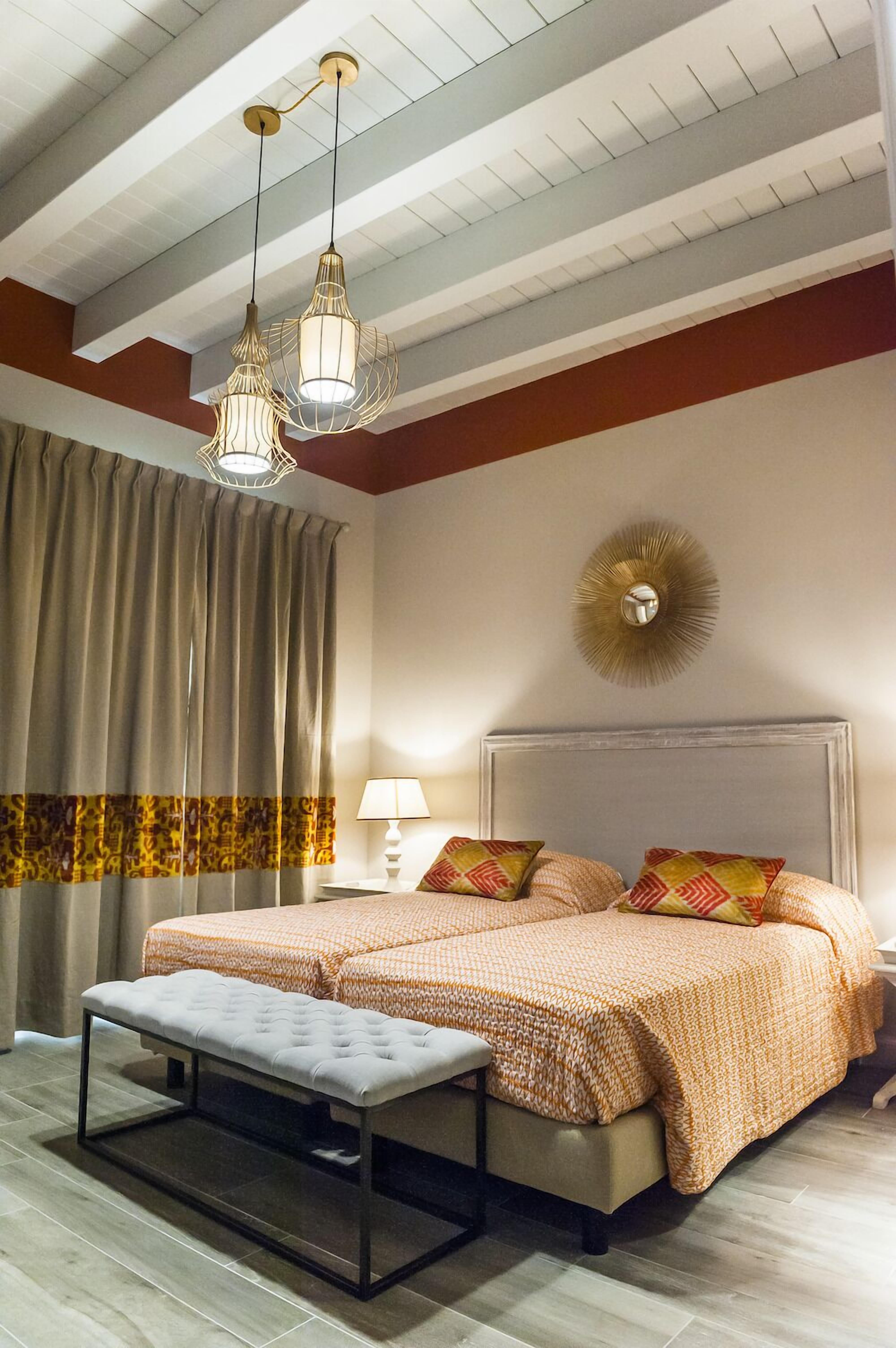 A bedroom with a large bed, a bench, a nightstand, and a wall clock.