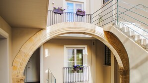 A building with a central archway, a staircase, and a balcony with flower baskets. - Hotel San Michele (Trapani)