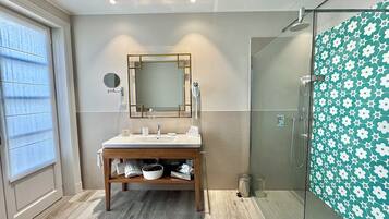 Un baño moderno con tocador de madera, un espejo grande, cabina de ducha de vidrio y pared con diseño.