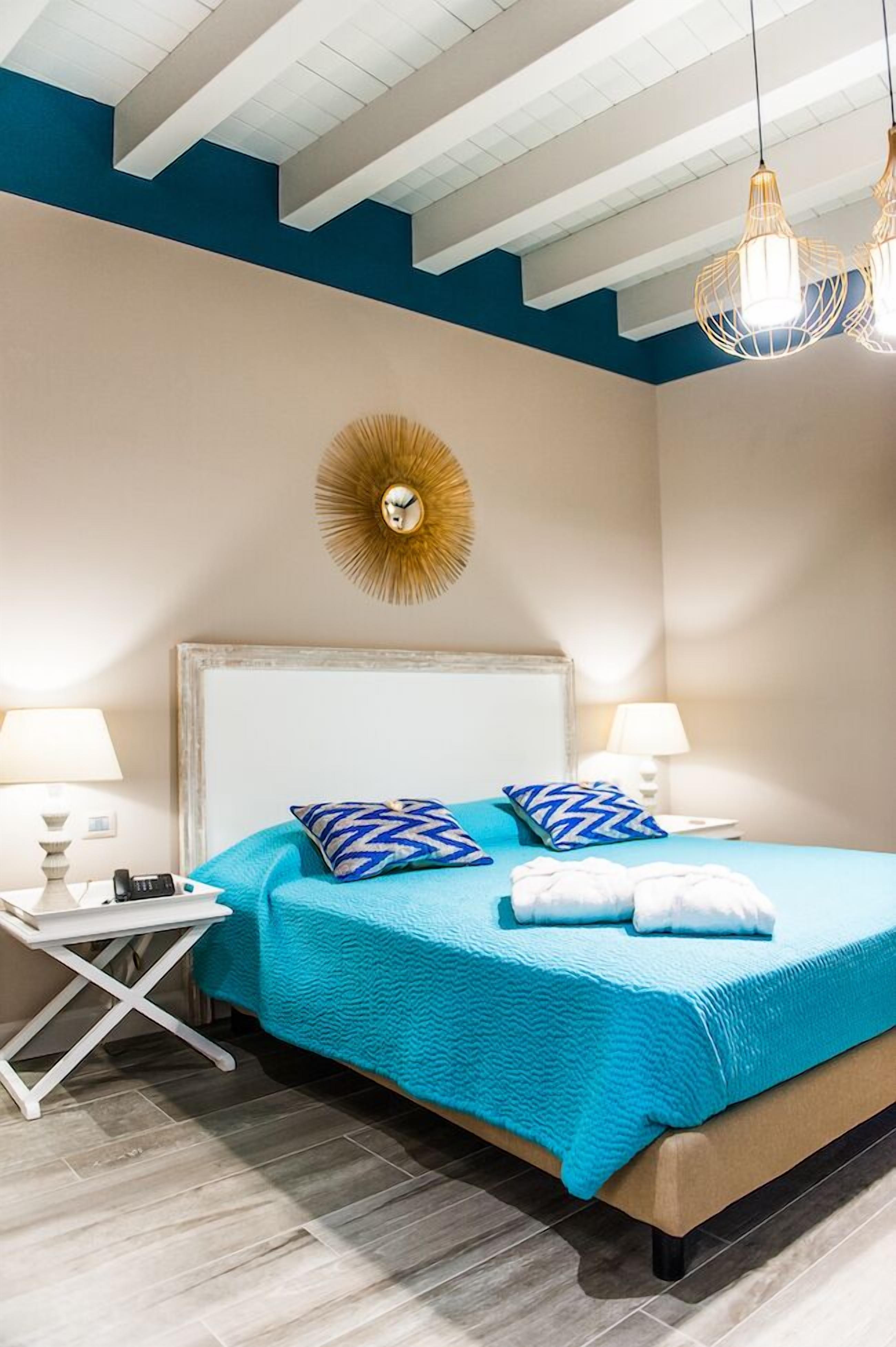A bedroom with a bed, two bedside tables, a wall clock, and a ceiling light fixture.