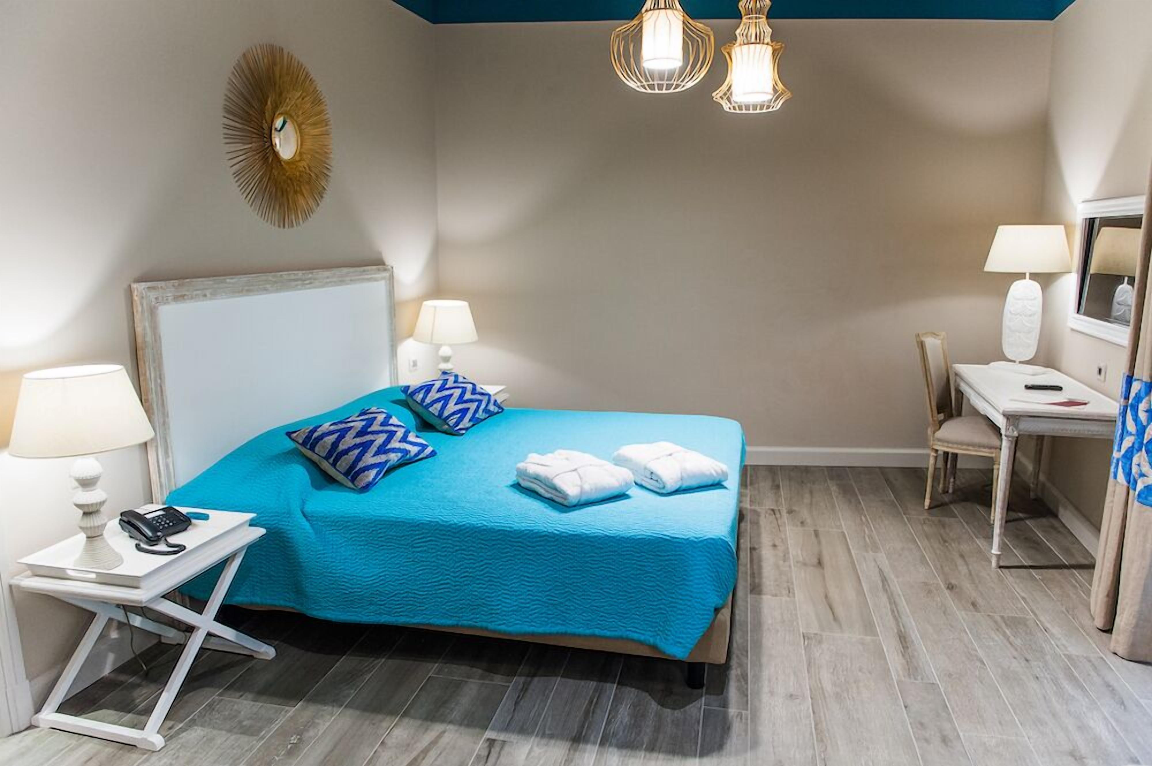 A hotel room with a bed, bedside lamps, a desk, and a chair.
