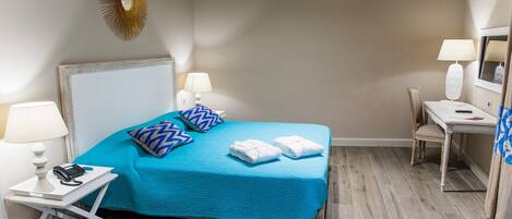 A hotel room with a bed, bedside lamps, a desk, and a chair.