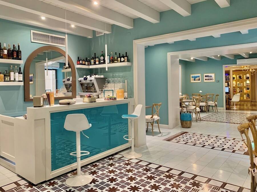 Een bar met krukken, een toonbank en flessen op planken.