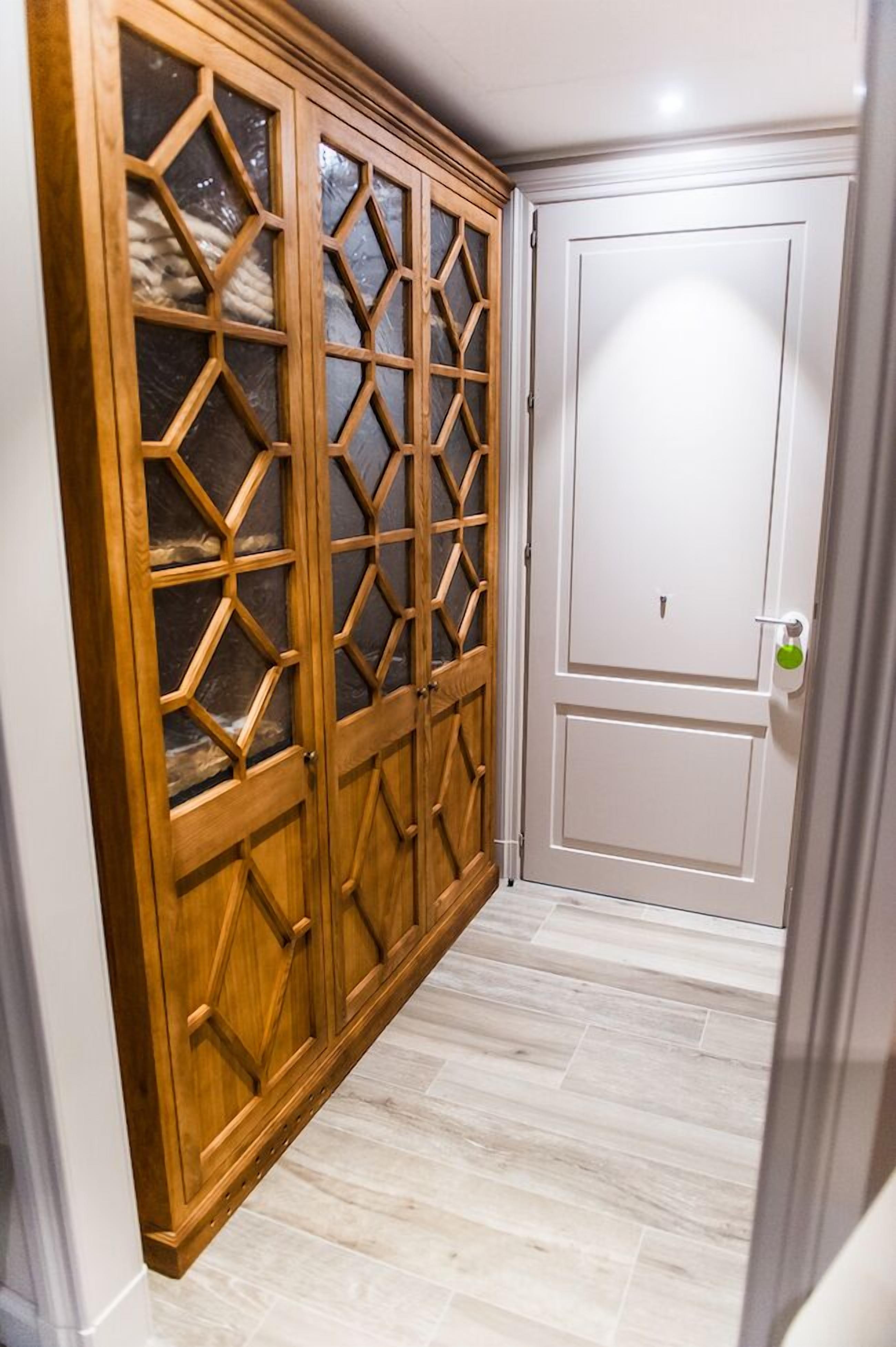 A hallway with a wooden wardrobe with glass doors and a white door.
