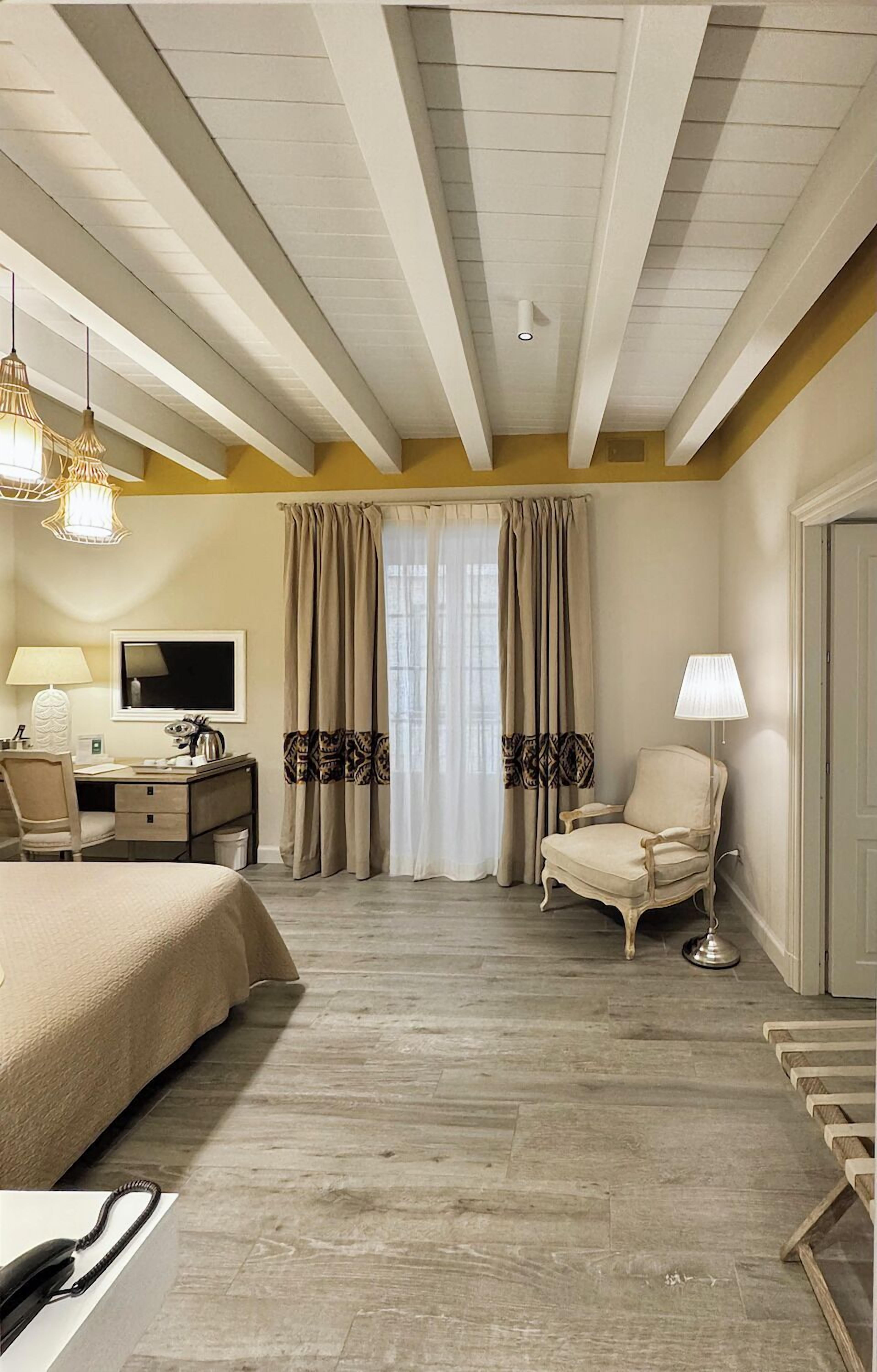 A hotel room with a bed, desk, chair, and a TV.
