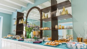A buffet setup with various food items, including pastries and fruits, arranged on a counter with a glass top. - Hotel San Michele (Trapani)