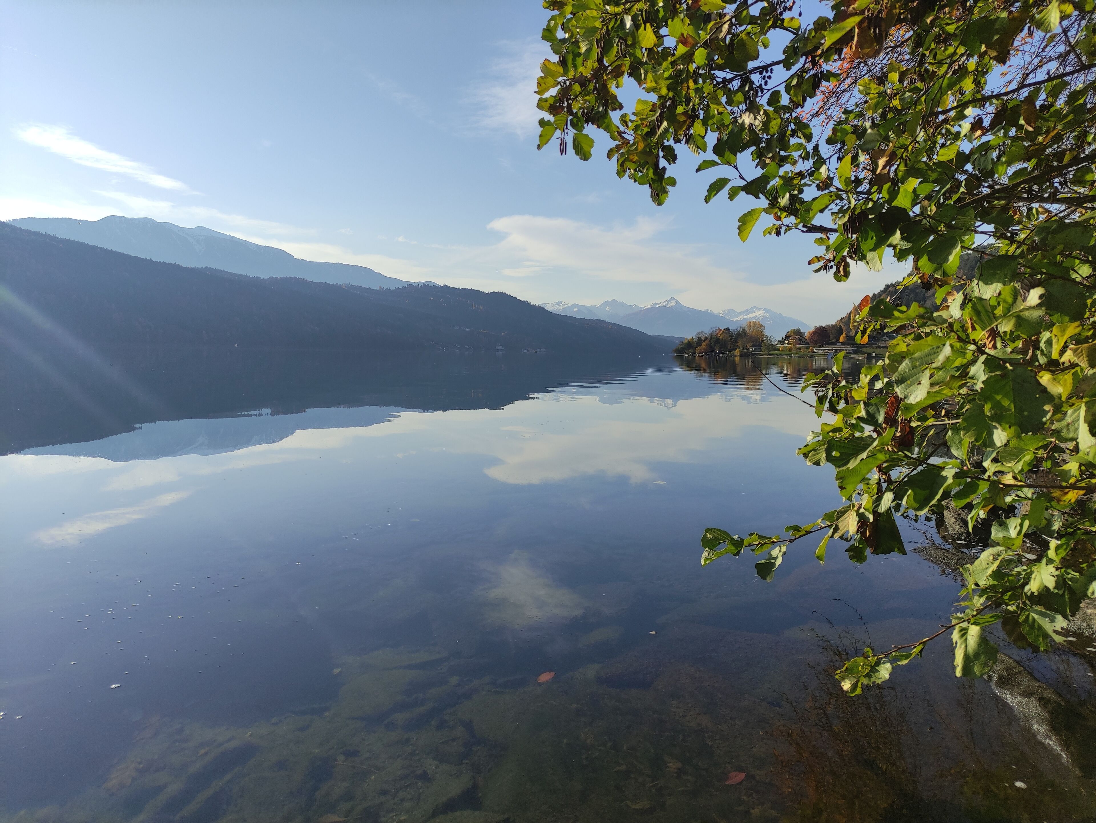 Un llac tranquil amb muntanyes al fons i un cel serè.