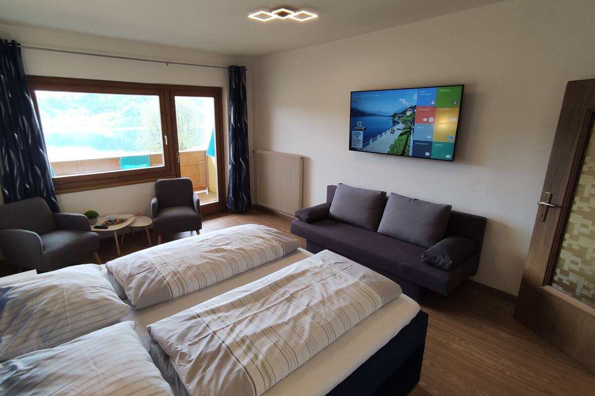 A hotel room with two beds, a sofa, a small table, and a TV.