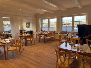 A spacious dining area with multiple tables and chairs, large windows with views, and a clean, modern interior. - Landhotel Franck (Brietlingen)