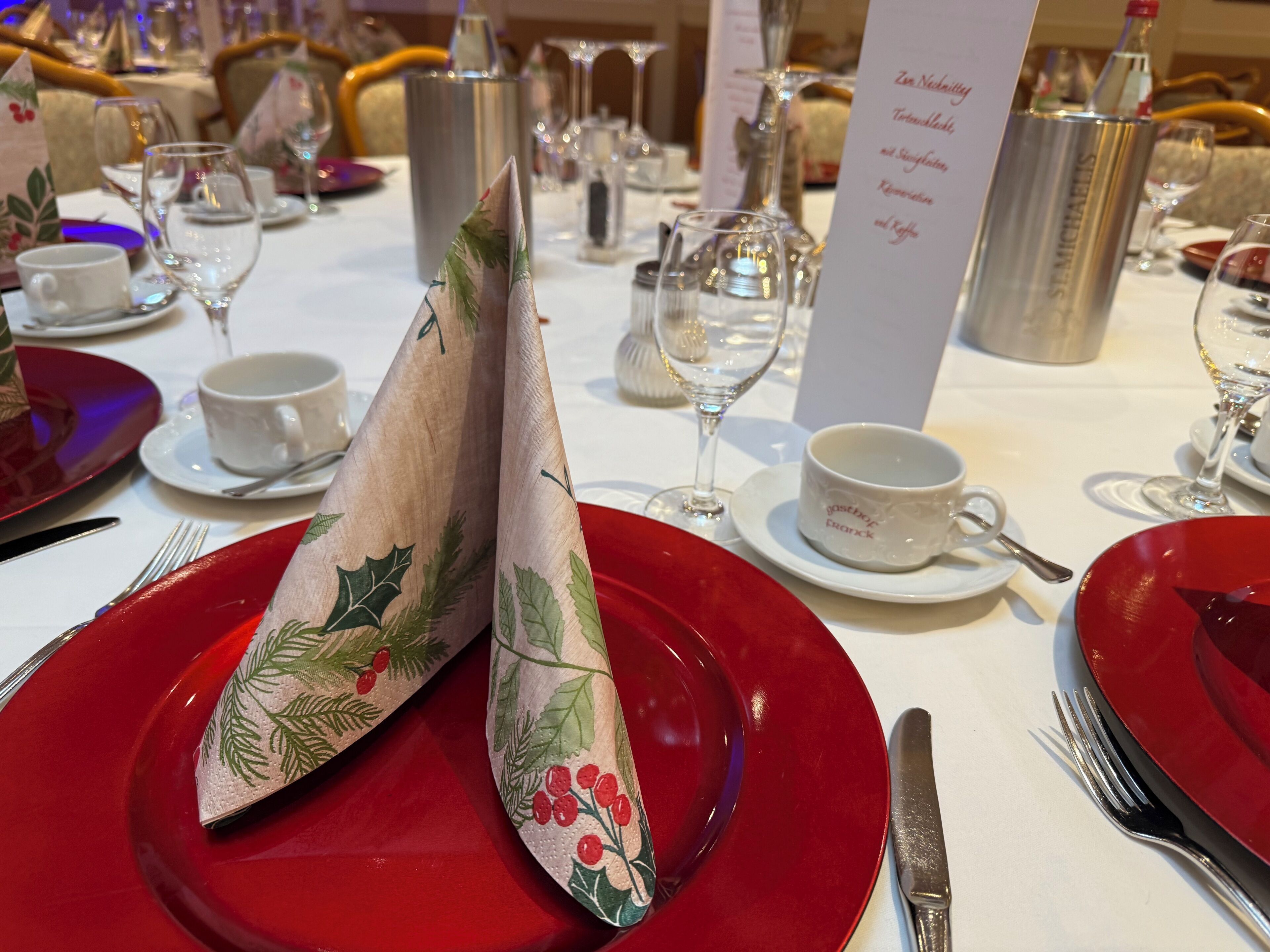 A table set with red plates, silverware, and a menu stand.