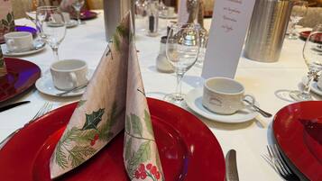 A table set with red plates, silverware, and a menu stand.