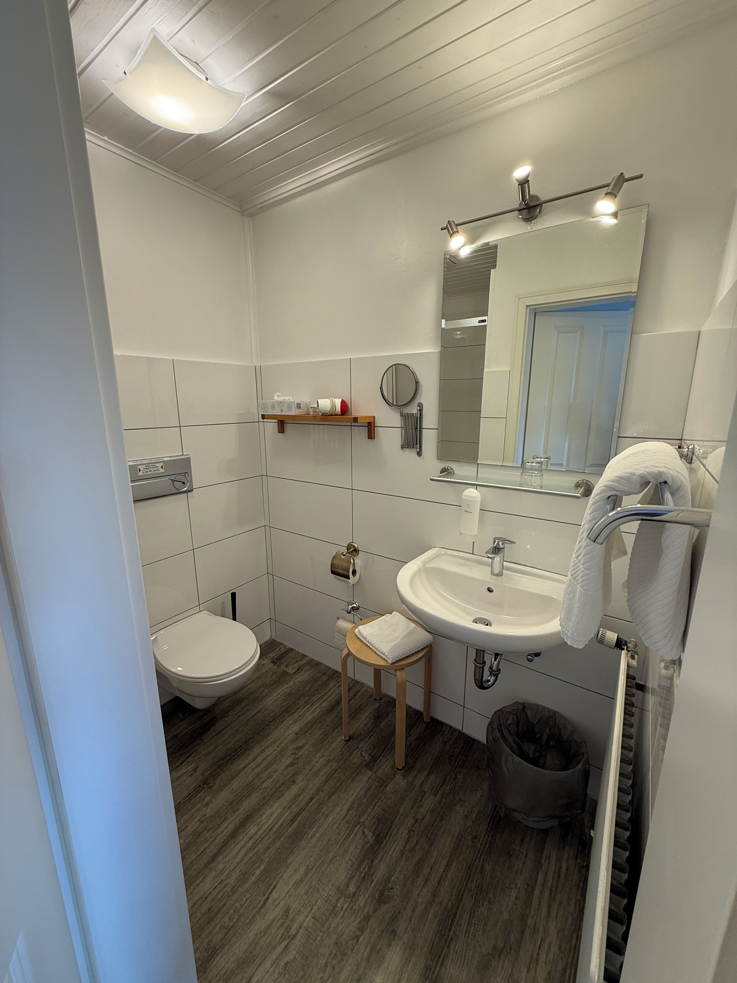 A bathroom with a toilet, sink, mirror, and towel rack.