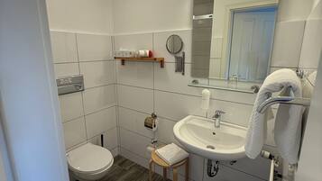 A bathroom with a toilet, sink, mirror, and towel rack.