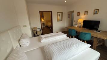 A hotel room with a bed, a desk, two chairs, a television, and a mirror.
