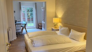 A hotel room with a large bed, a desk, and a chair, a lamp, and a view of the outdoors. - Landhotel Franck (Brietlingen)