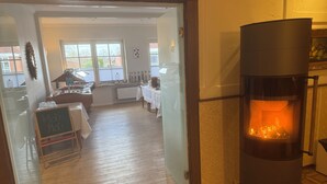 A cozy room with a fireplace, a dining area with a table and chairs, and a view of the outside through a window. - Landhotel Franck (Brietlingen)