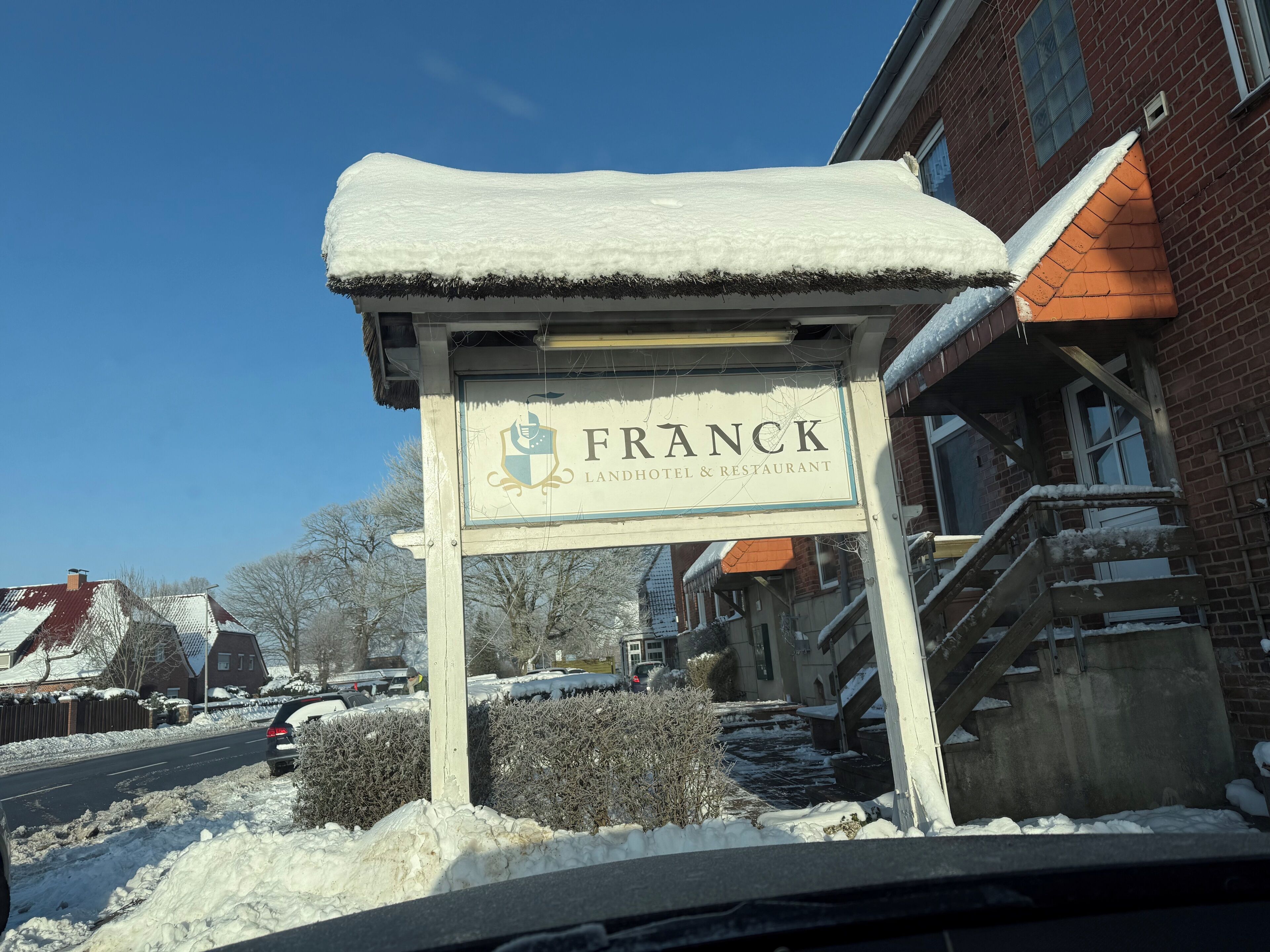 Señal nevada del Hotel & Restaurante Franck, con un edificio de ladrillo al fondo.