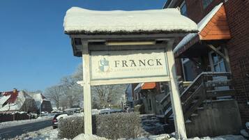 Señal nevada del Hotel & Restaurante Franck, con un edificio de ladrillo al fondo.