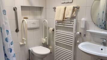 A modern bathroom with a toilet, bidet, hand dryer, towel rack, and a sink.