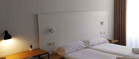 Ein Hotelzimmer mit zwei Betten, einem Schreibtisch, einem Stuhl und einer Lampe.