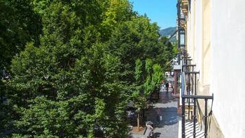Una calle estrecha con peatones y bicicletas aparcadas, rodeada de árboles y edificios.