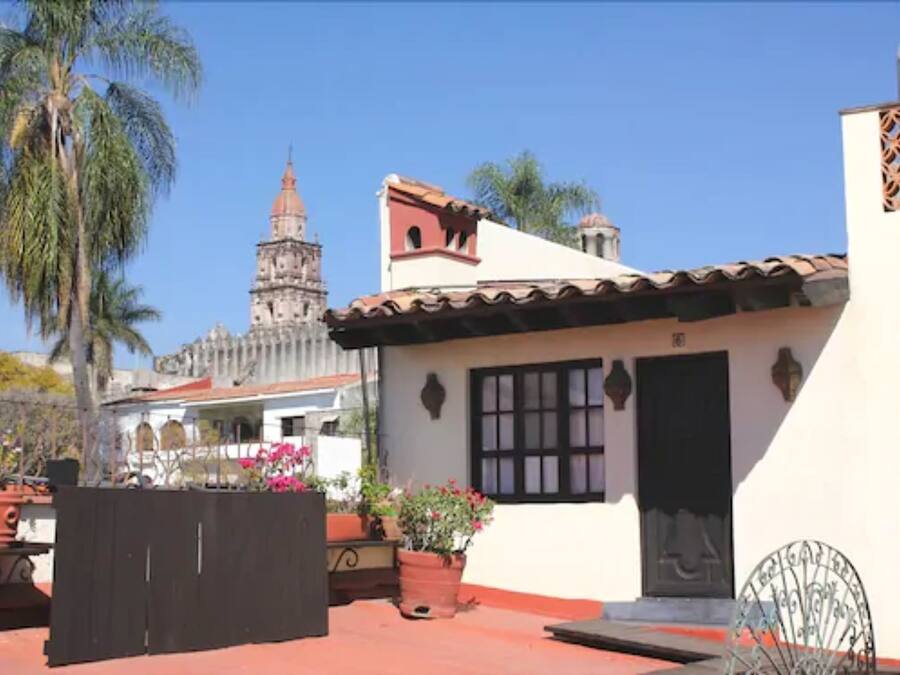 Un edificio con techo de tejas, un pequeño balcón y una puerta con marco de metal decorativo.