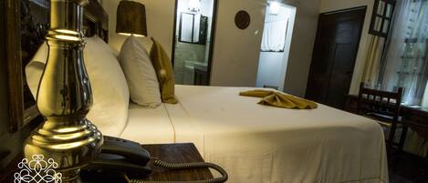 Habitación de hotel con cama, teléfono, espejo y ventana.