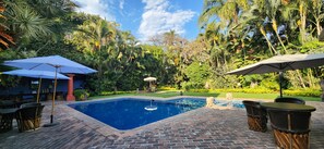 Una piscina al aire libre, sombrillas, sillones reclinables de piscina