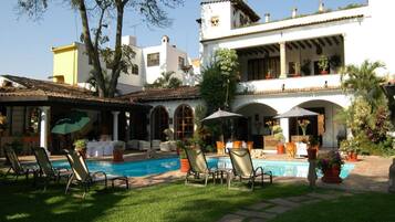 Alberca al aire libre, sombrillas en la alberca y camastros