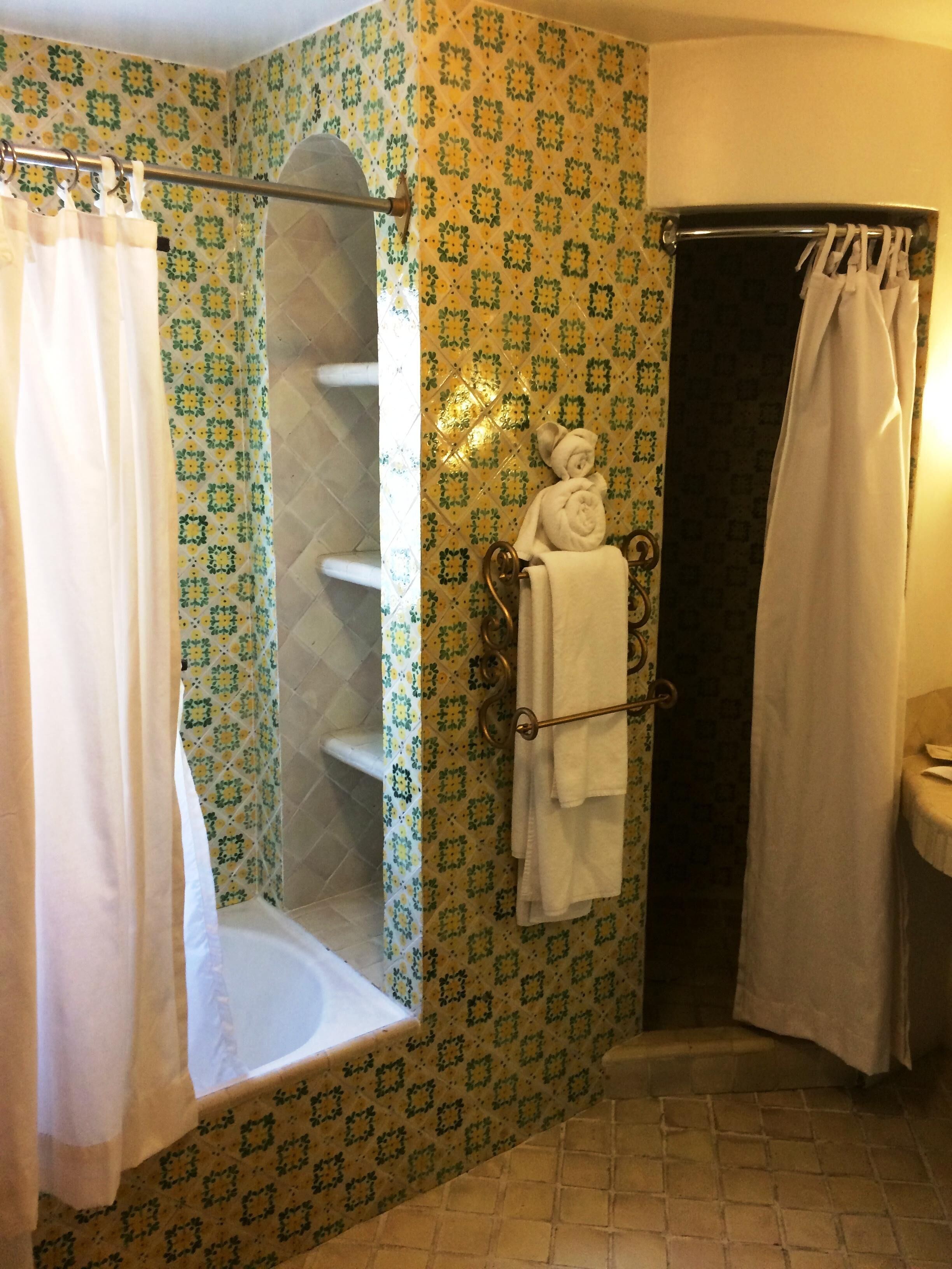 A bathroom with a shower, a towel rack, and a tiled wall.