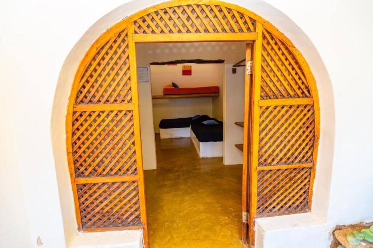 An arched doorway with a lattice design, leading to a room with bunk beds and a visible bedspread.
