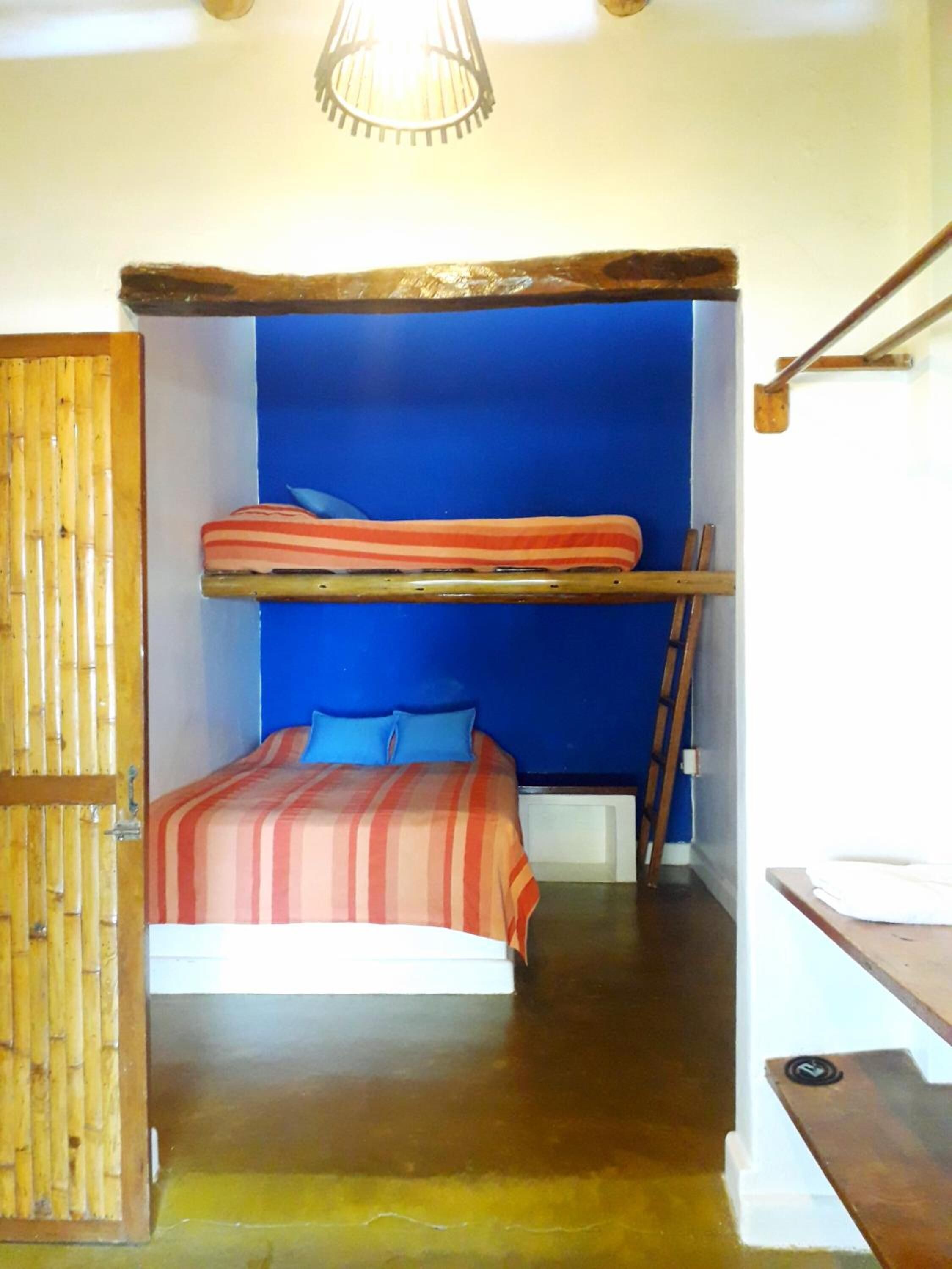 A room with a bunk bed, a wooden ladder, and a blue wall.