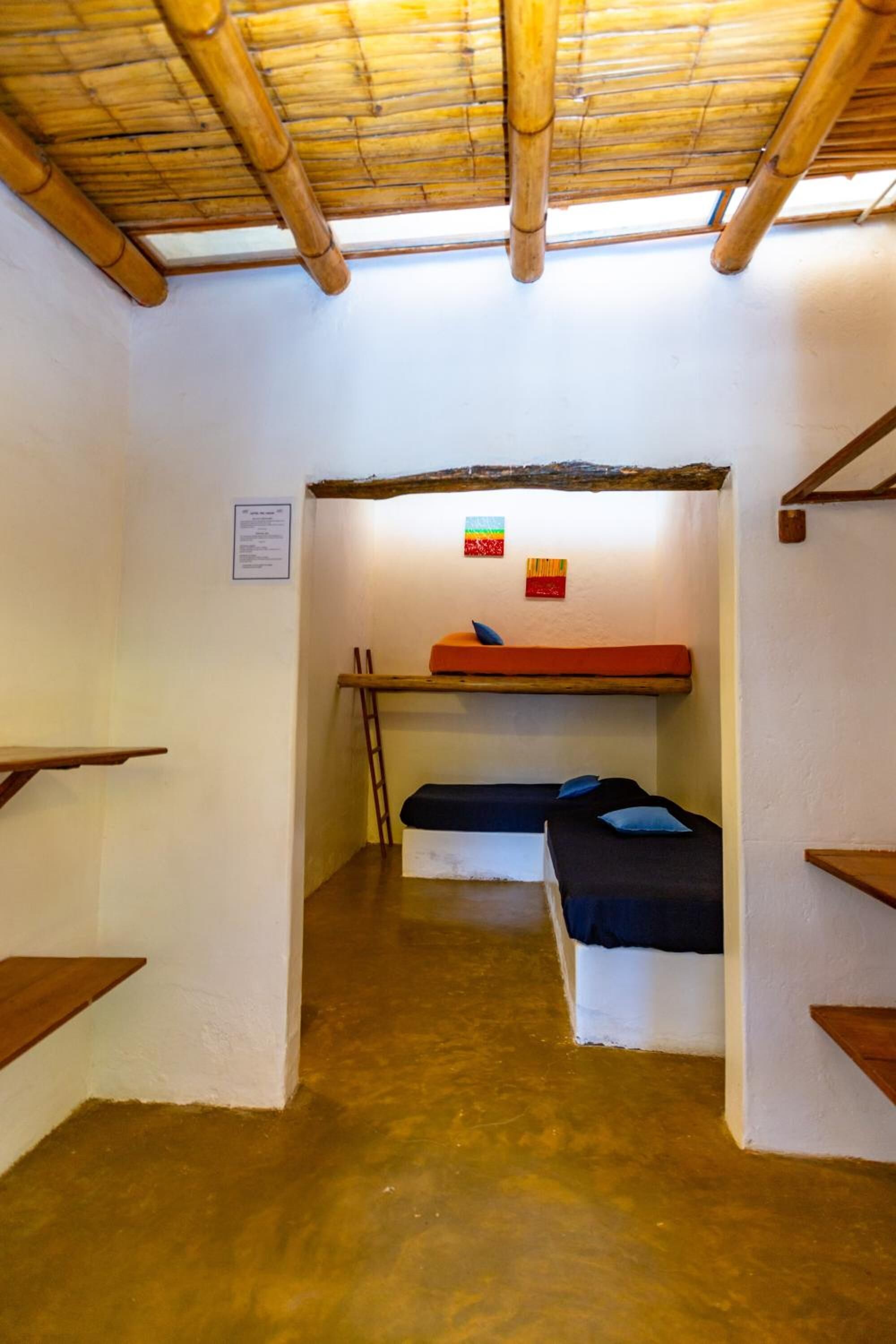 A small, compact room with bunk beds, a wooden ladder, and a bamboo ceiling.