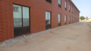 A red brick building with large windows and a concrete walkway. - Days Inn by Wyndham Alva (Alva)