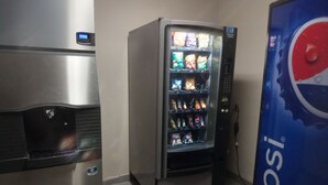 A vending machine with snacks and a Pepsi logo, a stainless steel refrigerator, and a tiled floor. - Days Inn by Wyndham Alva (Alva)