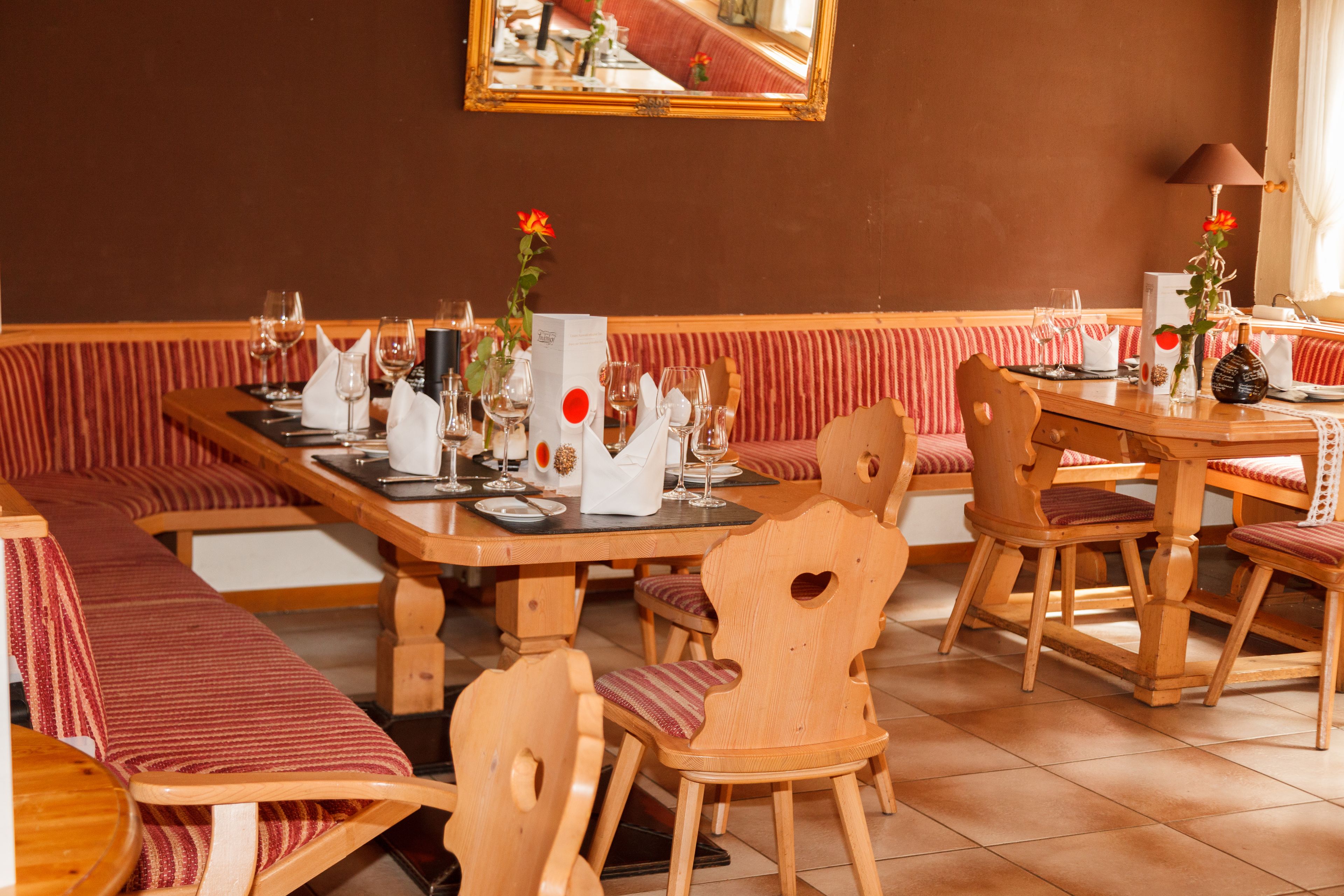 A restaurant with wooden furniture, red-striped benches, and a tiled floor.