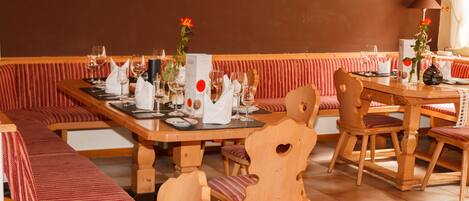 A restaurant with wooden furniture, red-striped benches, and a tiled floor.
