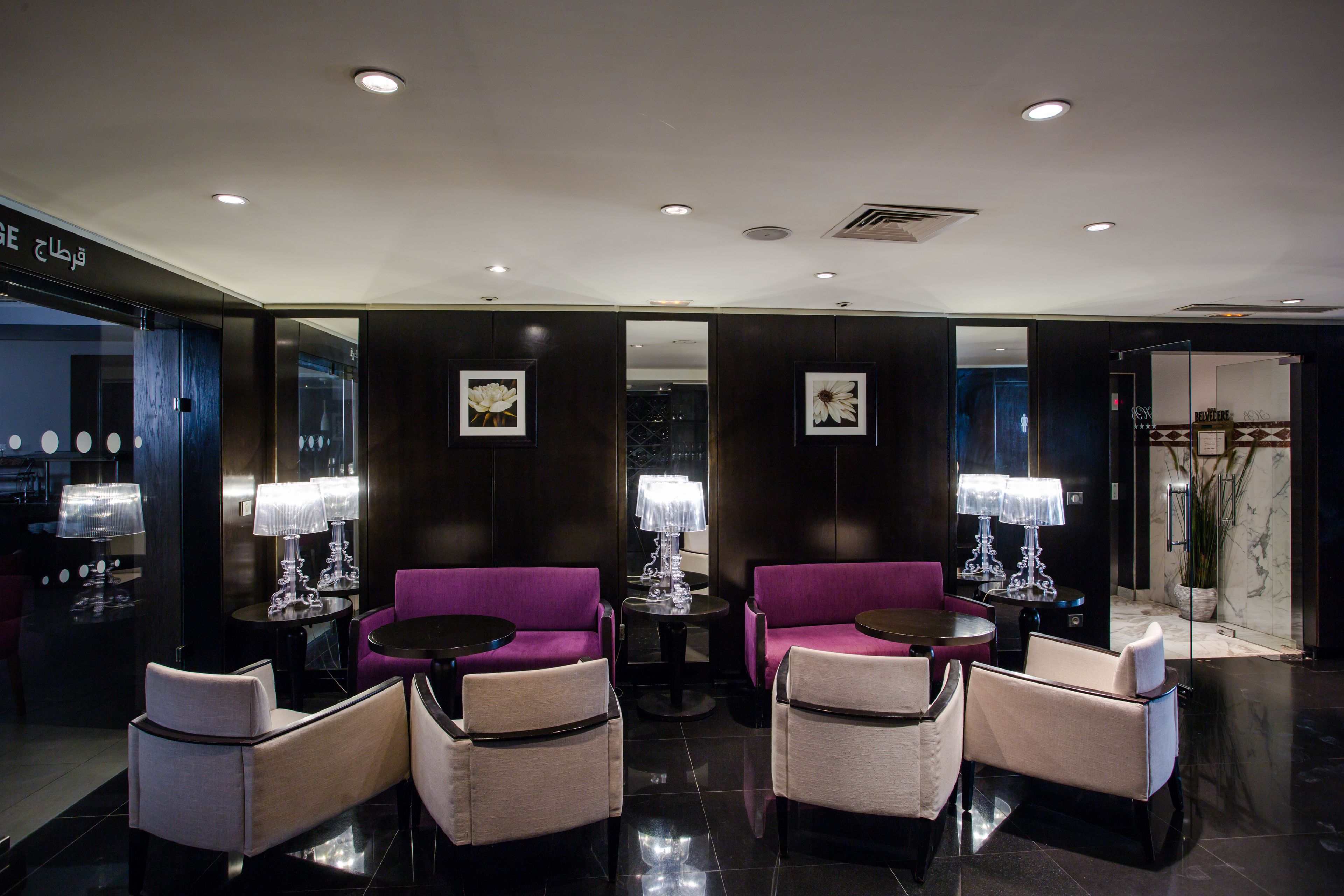 Eine moderne Lobby mit dunklen Holzpaneelen, violetten Sofas und einer Marmor-Rezeptionstresen.
