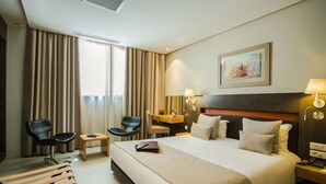 Una habitación de hotel con una cama grande, dos sillas, un escritorio y una mesita de noche.