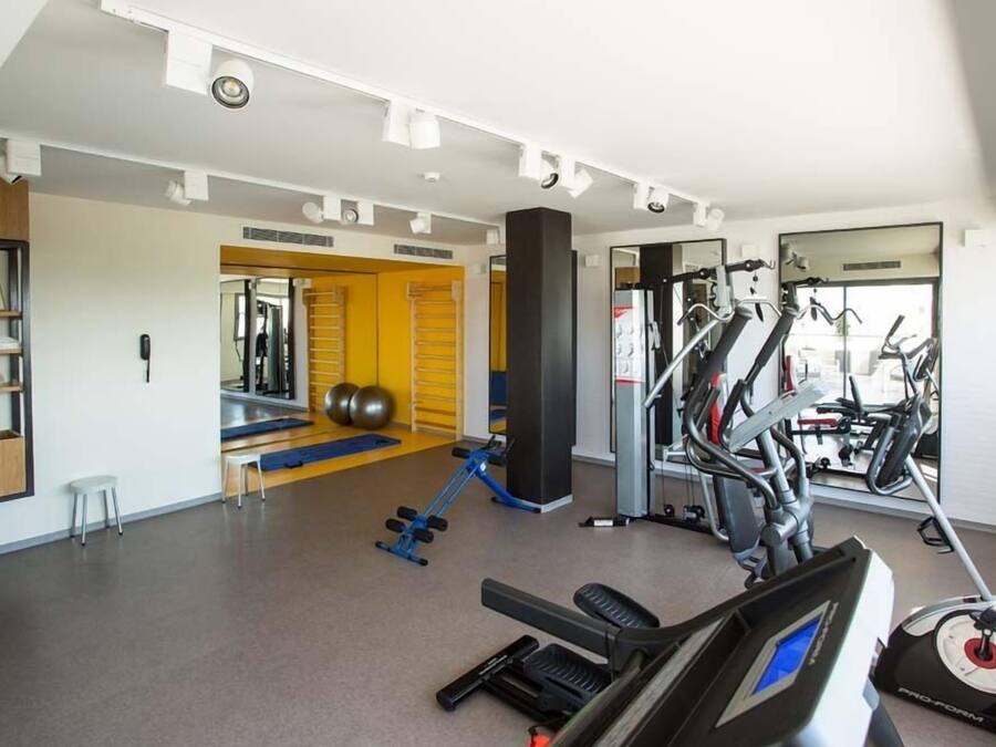 Uma academia com equipamentos de cardio, máquinas de peso e um espelho.
